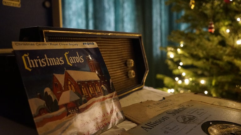Vintage records sit in front of a record player, a christmas tree shines in the background
